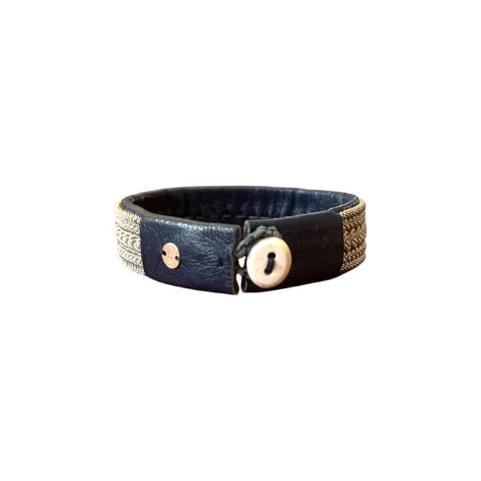 Handgjort brett armband i renskinn med täta tenntrådsflätor och renhornsknapp, inspirerat av Áhkká-massivet och en hyllning till starka kvinnor och nordiskt hantverk.