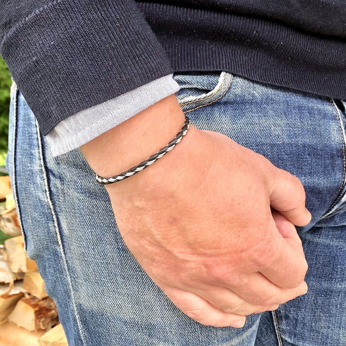 Handgjort smalt armband i renskinn med tenntrådsfläta och renhornsknapp, inspirerat av slingrande stigar i nordisk natur.