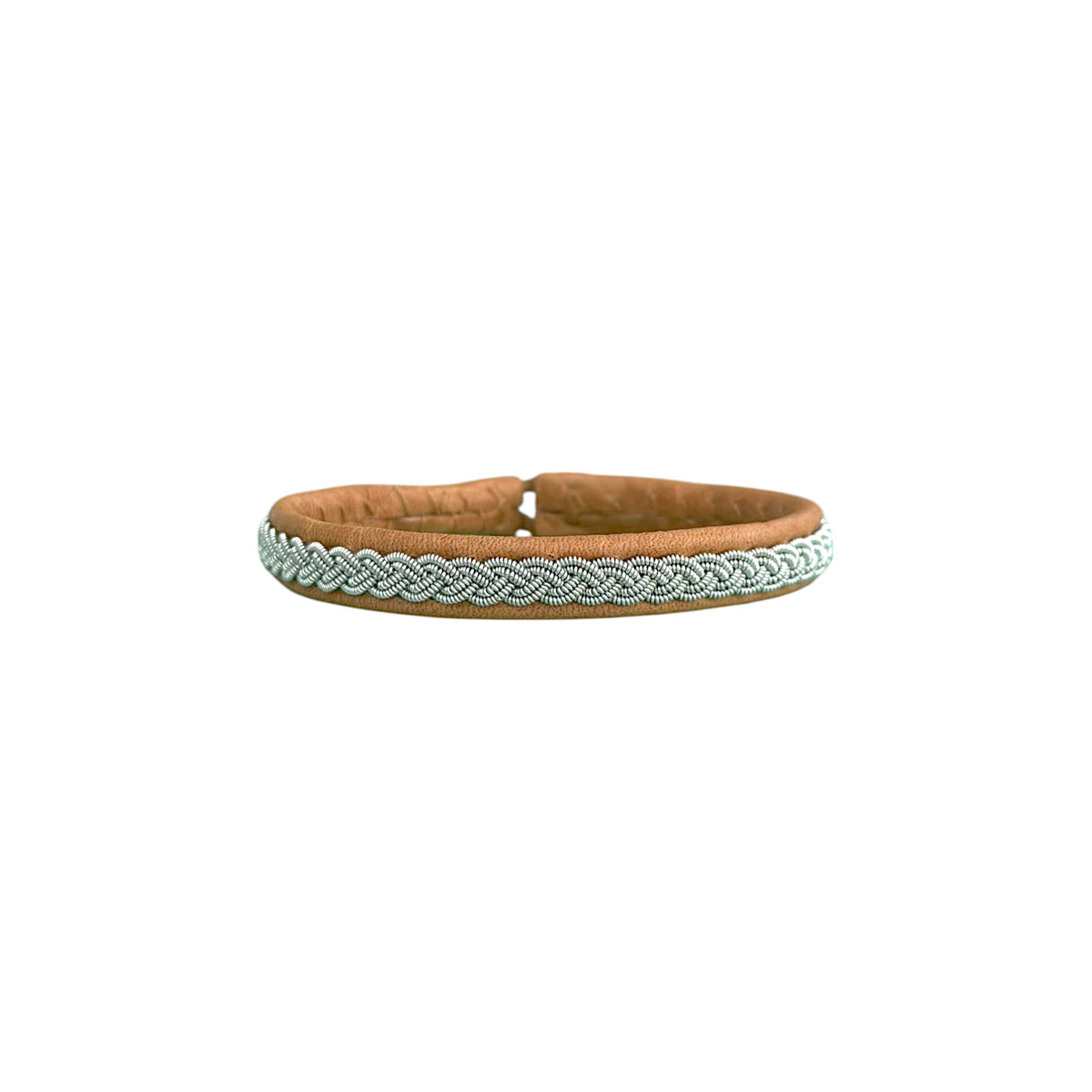 VINTER är ett handgjort armband i renskinn med traditionell tenntrådsfläta, inspirerat av vinter, samiskt arv och den nordiska naturens stillhet.