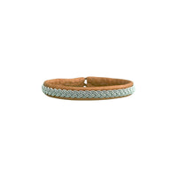 VINTER är ett handgjort armband i renskinn med traditionell tenntrådsfläta, inspirerat av vinter, samiskt arv och den nordiska naturens stillhet.