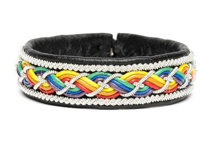 Handgjort tennarmband i renskinn med färgstark fläta i regnbågsfärger och renhornsknapp, symboliserar frihet och mångfald och pride