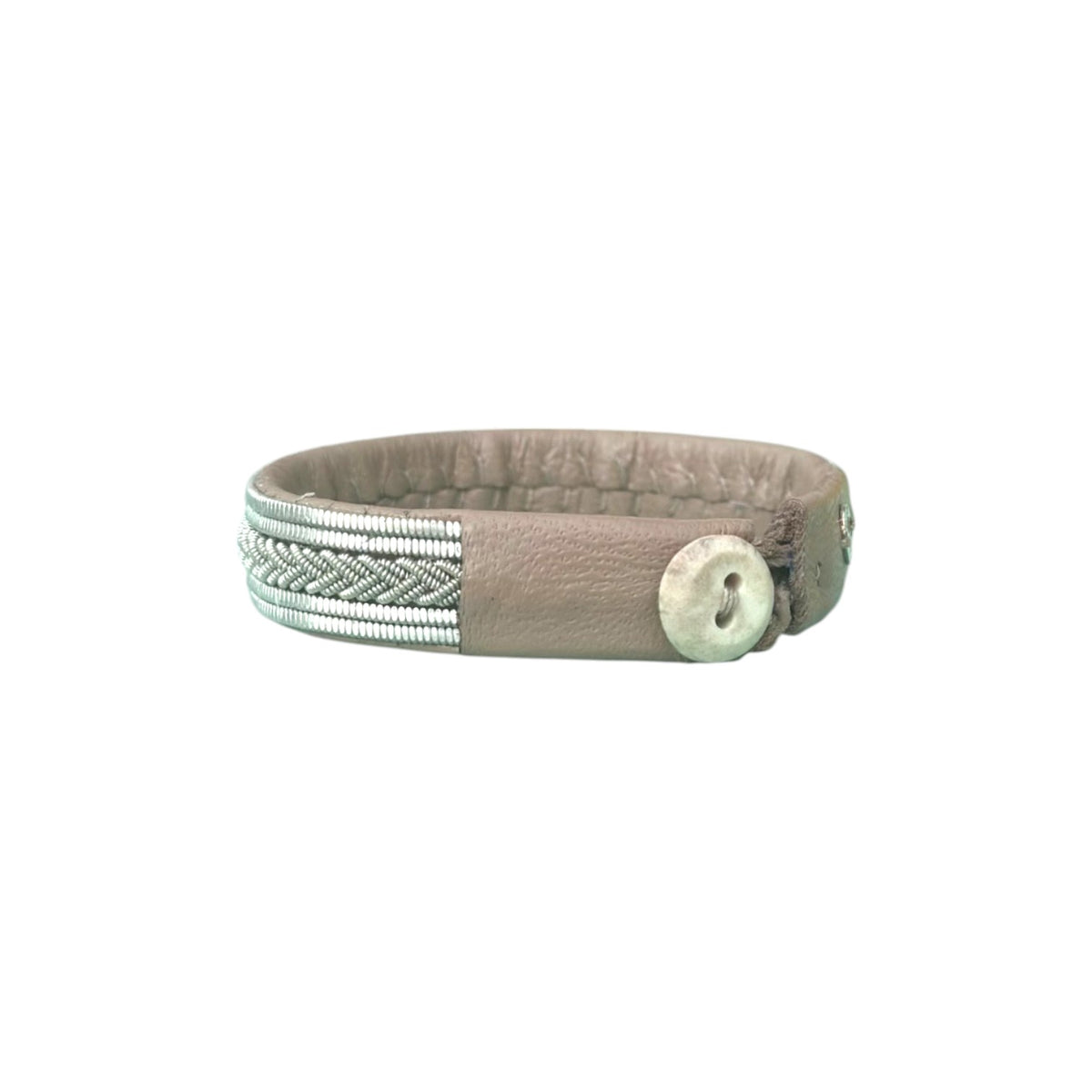 Handgjort armband i renskinn med tenntrådsfläta och renhornsknapp, inspirerat av frostens mönster och vinterns stillhet.
