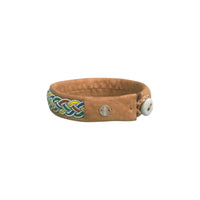 Handgjort armband i renskinn med färgstark tenntrådsfläta och renhornsknapp, inspirerat av den nordiska naturens färger och kulturarv.