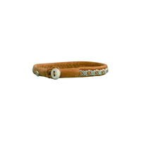 Handgjort smalt armband i renskinn med tenntrådsfläta och renhornsknapp, inspirerat av naturens lugn och nordisk enkelhet.
