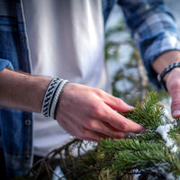 IS är ett handgjort tennarmband i renskinn med klassisk tenntrådsfläta och renhornsknapp – inspirerat av vinter, friluftsliv och nordisk tradition.