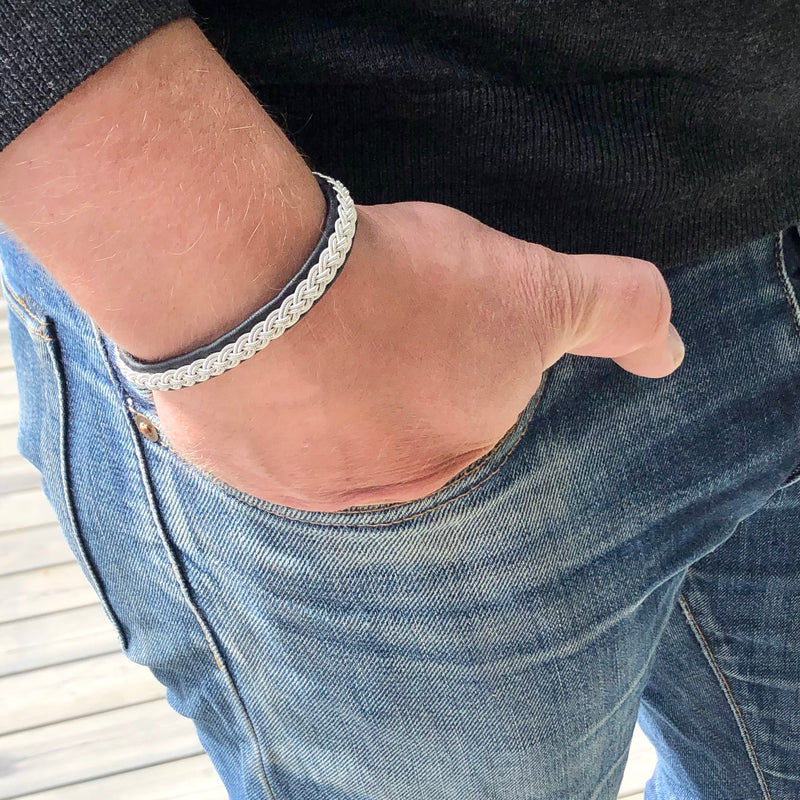 IS är ett handgjort tennarmband i renskinn med klassisk tenntrådsfläta och renhornsknapp – inspirerat av vinter, friluftsliv och nordisk tradition.
