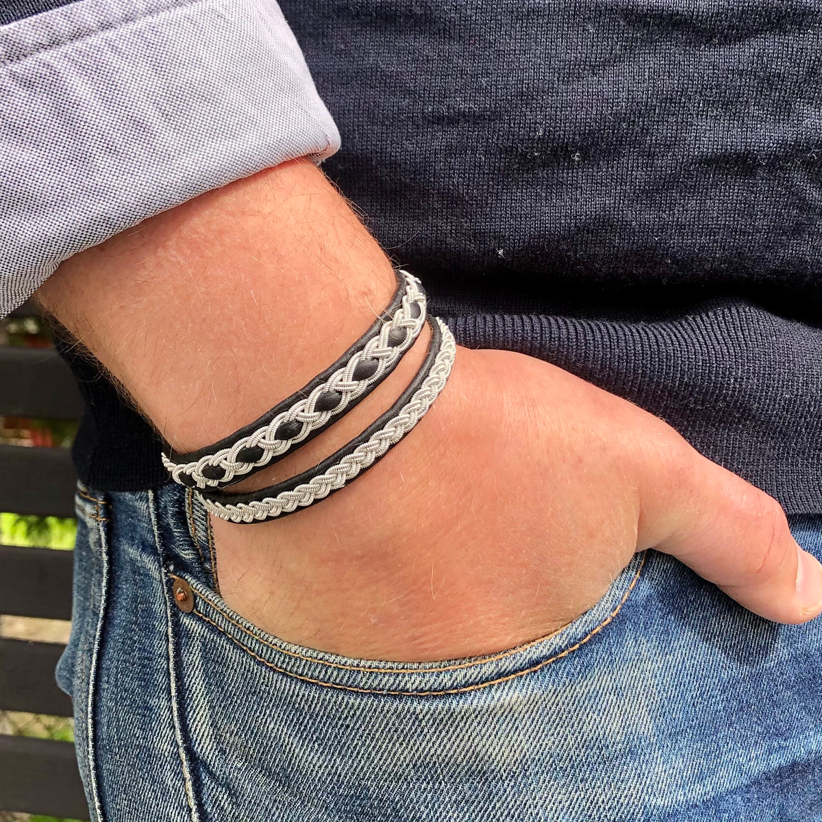 Handgjort armband i renskinn med tenntrådsfläta och renhornsknapp, inspirerat av den arktiska vildmarken

