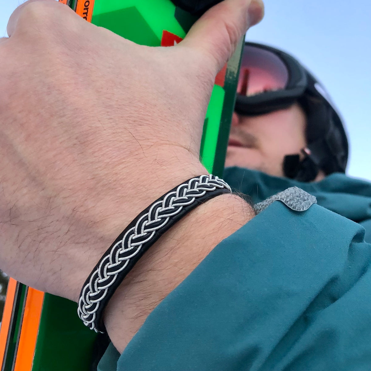 Handgjort tennarmband i renskinn med tenntrådsfläta och renhornsknapp
