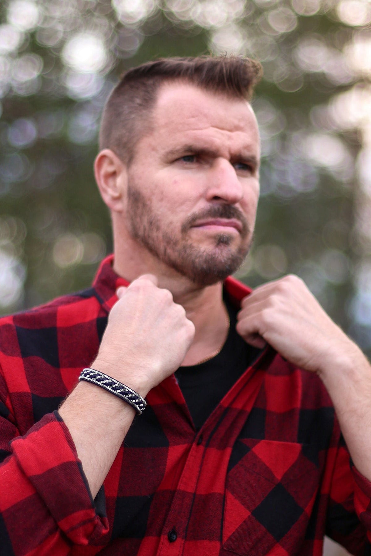 Man bär tennarmbandet Fjäll från Arctic Collection, ett handgjort armband, fotograferad utomhus i nordisk natur