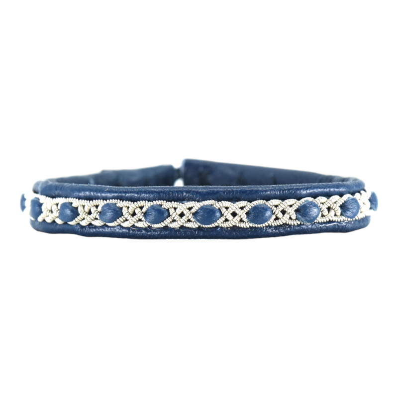 Handgjort smalt armband i renskinn med tennfläta och renhornsknapp, inspirerat av naturens lugn och nordisk enkelhet.
