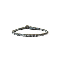 Handgjort tennarmband Stig från Arctic Collection i mörkgrönt renskinn med flätad läderrem och silverfärgad tenntråd. Armbandet visas mot vit bakgrund med renhornsknapp.